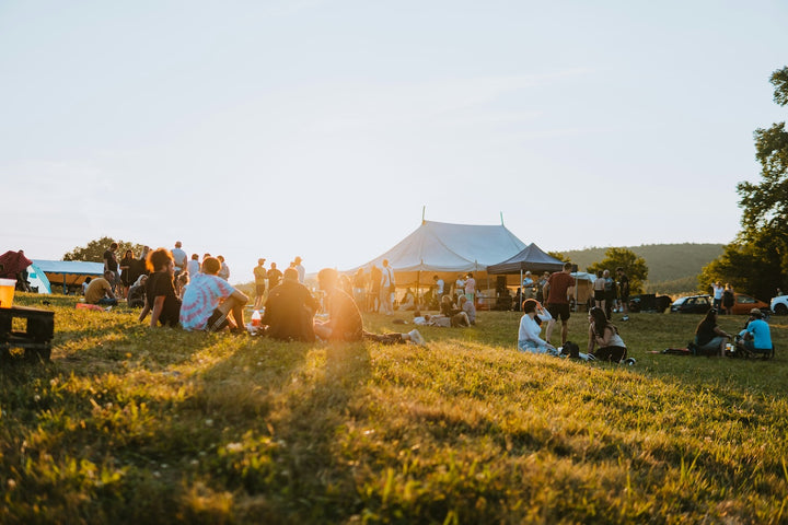 people sat outside at an outdoor event with a tent in the back ground